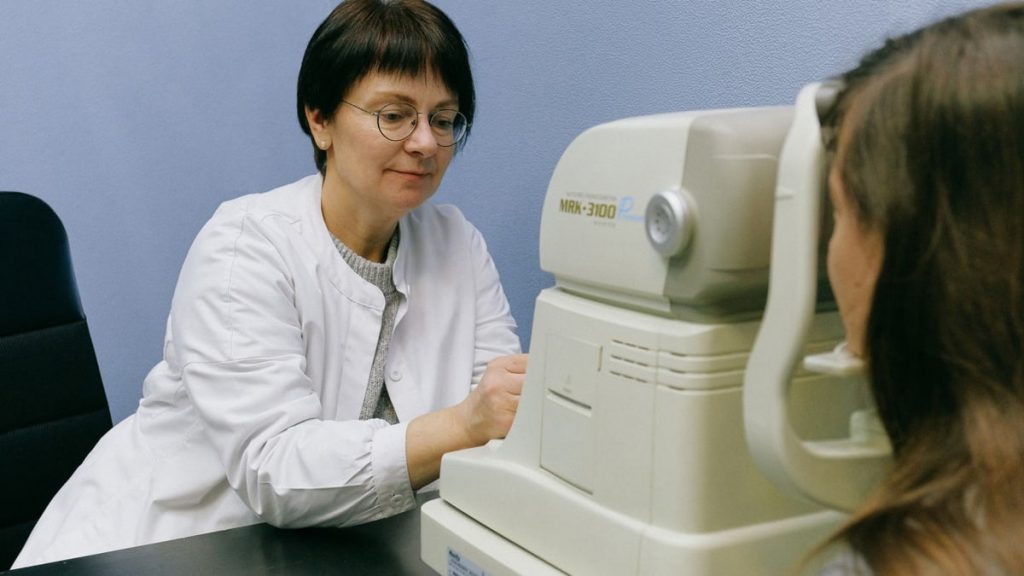 A healthcare professional conducts an eye exam using advanced technology in a clinical setting.